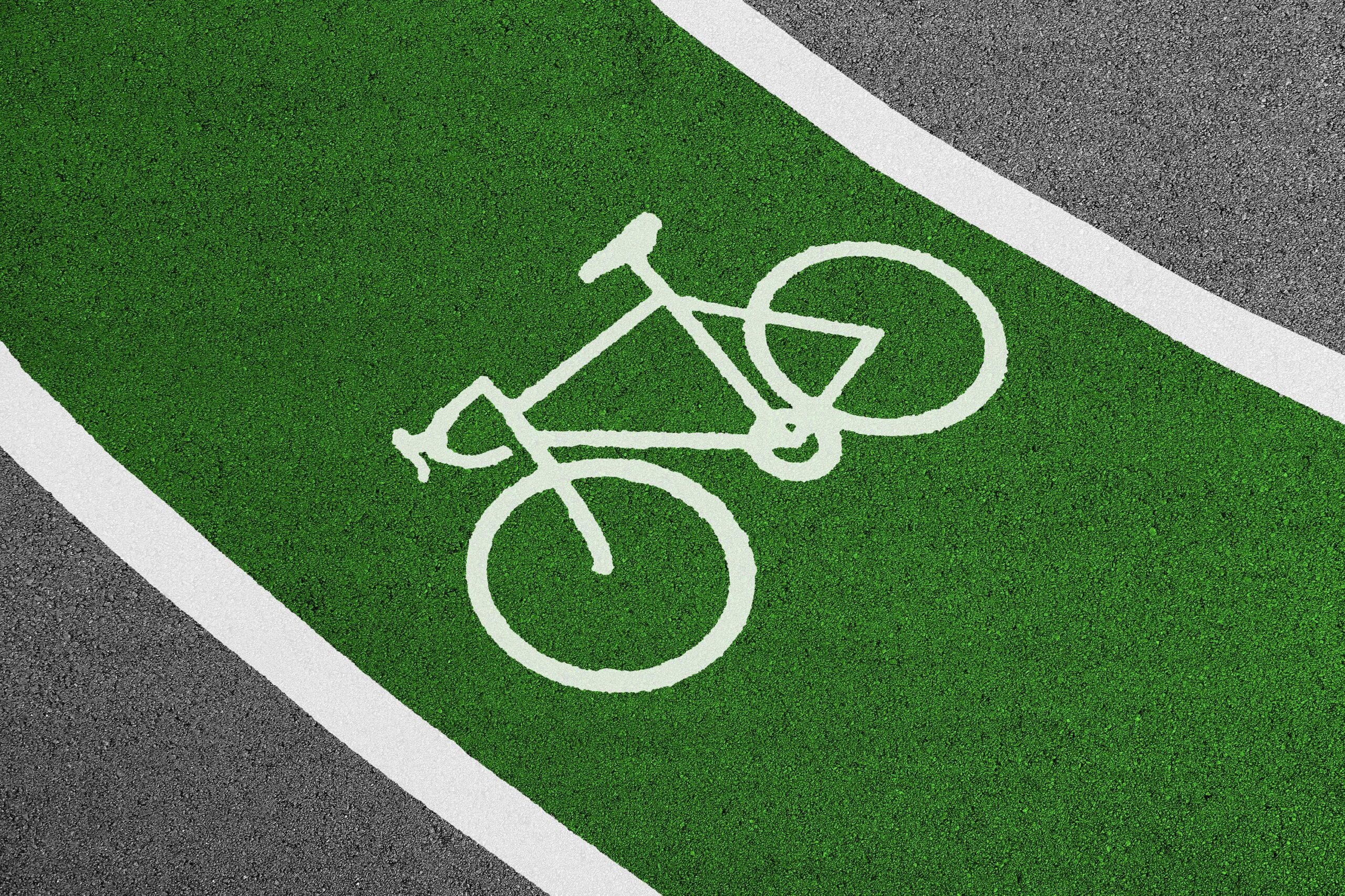 Bright green bicycle lane with white bike symbol and clear road texture.